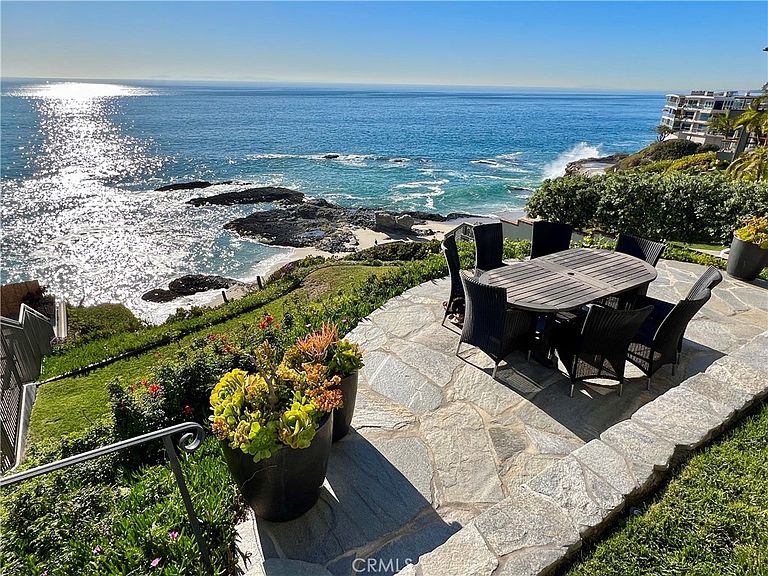 Flagstone patio with outdoor dining and crashing surf below the bluff